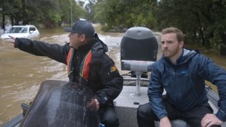 Volunteer rescue worker Mike Level and reporter Zach Toombs search for residents trapped by floodwaters.