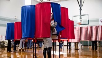A young woman peeks out of a voting booth