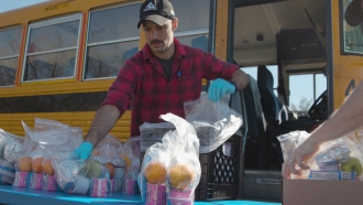 Rick Groger putting packets of food with oranges, milk and sandwichs on a table