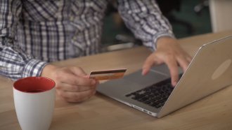 Man types credit card info into computer.