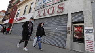 Women walk past closed shops in New York City