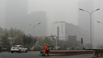 A man wearing a mask sweeps a street in Beijing