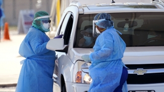 Medical personnel administer COVID-19 testing at a drive-through site.