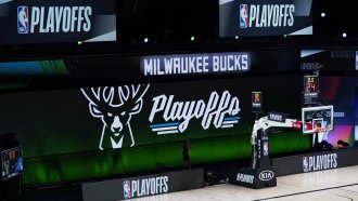 Milwaukee Bucks signage is displayed on screens beside an empty court before the scheduled start of an NBA basketball