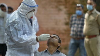 A health worker takes a nasal swab sample to test for COVID-19 at a government hospital in India.