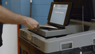 Man inserts ballot into scanning machine