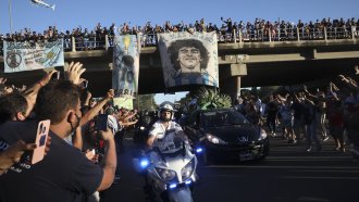 Mourning fans wave at the caravan carrying the remains of Diego Maradona to his resting place in Buenos Aires, Argentina.