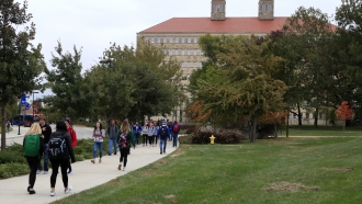 Students walk in front of Fraser Hall on the University of Kansas campus