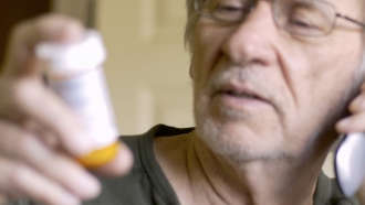 A man holds a pill bottle.