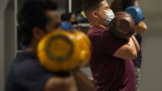 Juan Avellan, center, and others wear masks while working out in an indoor class at a Hit Fit SF gym.