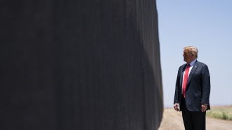 Donald Trump stands at border wall.