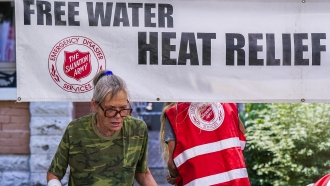 A pedestrian holds a bottle of cold water at a Salvation Army hydration station