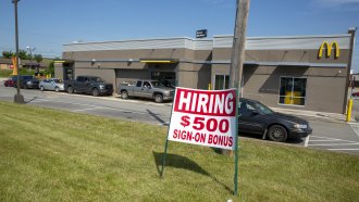 A hiring sign offering a $500 bonus is posted in front of a McDonald's.