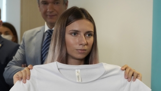 Belarusian Olympic sprinter Krystsina Tsimanouskaya holds up an Olympic-related T-shirt with the slogan "I Just Want to Run."