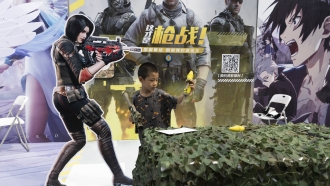 A child plays with a toy gun during a promotion for online video games in Beijing, China.