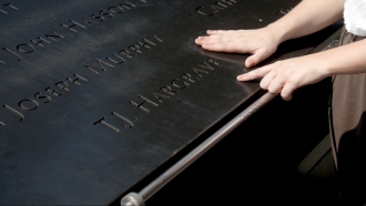 Amy Hargrave points to her father's name on the 9/11 Memorial in New York City.