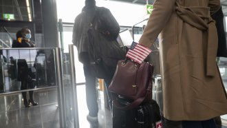 A woman walks through the boarding area at Frankfurt airport with a U.S. flag