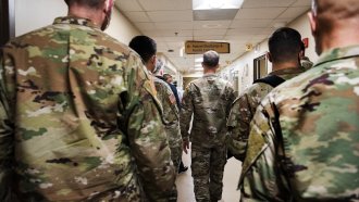 Soldiers walk through a hospital hallway.