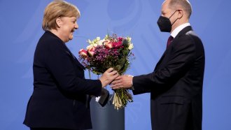 Newly elected German Chancellor Olaf Scholz gives flowers to former Chancellor Angela Merkel