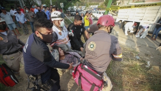 An injured migrant woman is moved by rescue personnel from the site of an accident