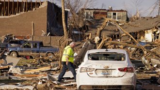 A man walks through destruction left by a tornado.