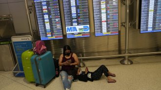 Travelers lay underneath a screen at the airport.
