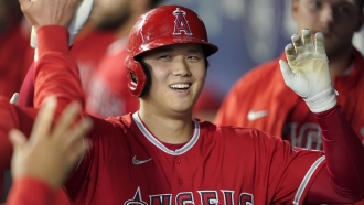 Shohei Ohtani is greeted in the dugout after he hit a home run during the first inning against the Seattle Mariners.i