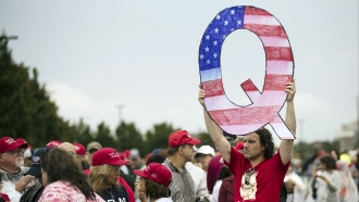 A protestor holds a Q sign for QAnon.