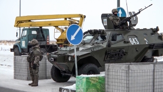 A Kazakhstan soldier stands next to a military vehicle at a check point