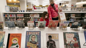 A woman and her daughter browse books at a library.