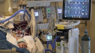 A COVID-19 patient is attached to life-support systems in the ICU.