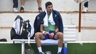 Tennis star Novak Djokovic sits on a bench