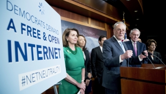 Democrats stand next to sign calling for net neutrality.