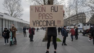 Demonstrator in Paris holds a placard that reads 'No to vaccine pass' in French