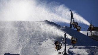 Snowmaking machines spray artificial snow on a ski slope