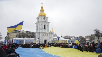 Activists hold a huge Ukrainian national flag outside of St. Michael cathedral in Kyiv, Ukraine