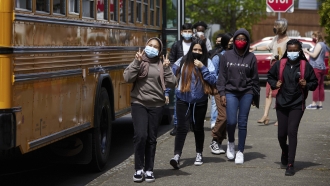Middle school students wearing masks get off the bus