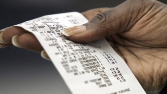 Woman checks her sales receipt after checking out from grocery store