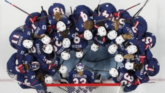 United States players gather in front of the net before a women's semifinal hockey game