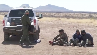 Border patrol agents detain migrants trying to cross the border.
