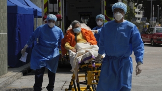 A patient on hospital bed is escorted to the temporary holding area outside Caritas Medical Centre in Hong Kong