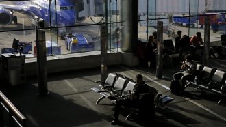 Travelers sit at in an airport.