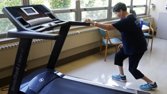 A woman stretches before she walks on a treadmill