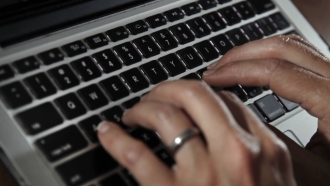 A person types on a laptop keyboard