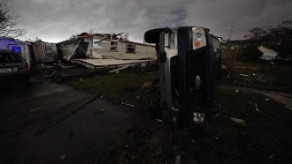 A truck lies on this side in front of a destroyed home after a tornado swept through New Orleans