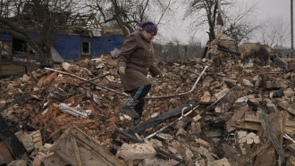 Mariya, a local resident, looks for personal items in the rubble of her house.