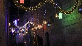 A Palestinian man hangs decorative lights in preparation for the holy Muslim month of Ramadan