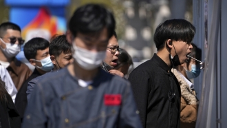 Workers wearing face masks to help protect from the coronavirus line up to get their throat swab