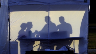 Medical personnel are silhouetted against the back of a tent before the start of coronavirus testing