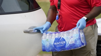 A person holds a pack of water bottles.